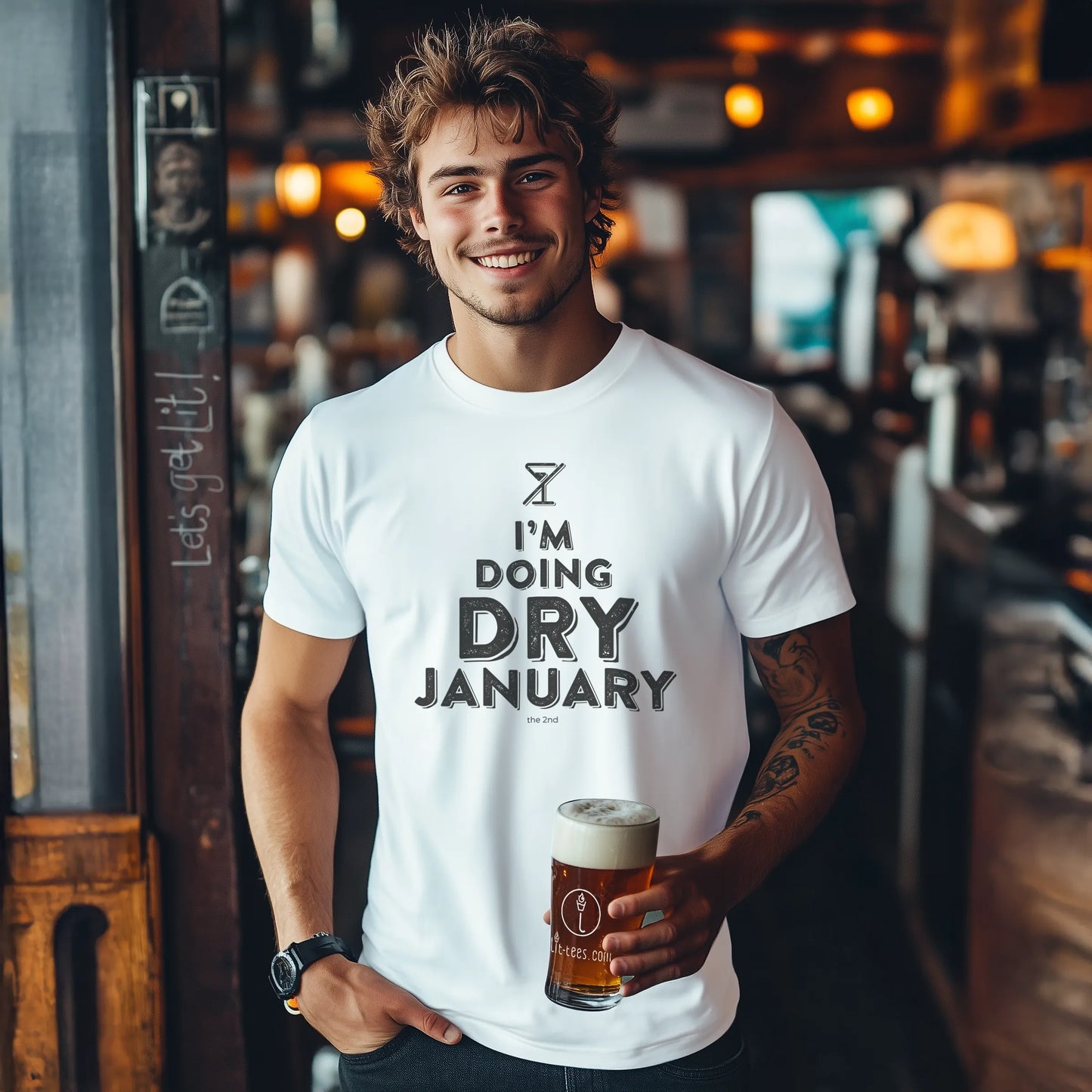 Man wearing a 'I'm Doing Dry January' t-shirt holding a beer in a bar.