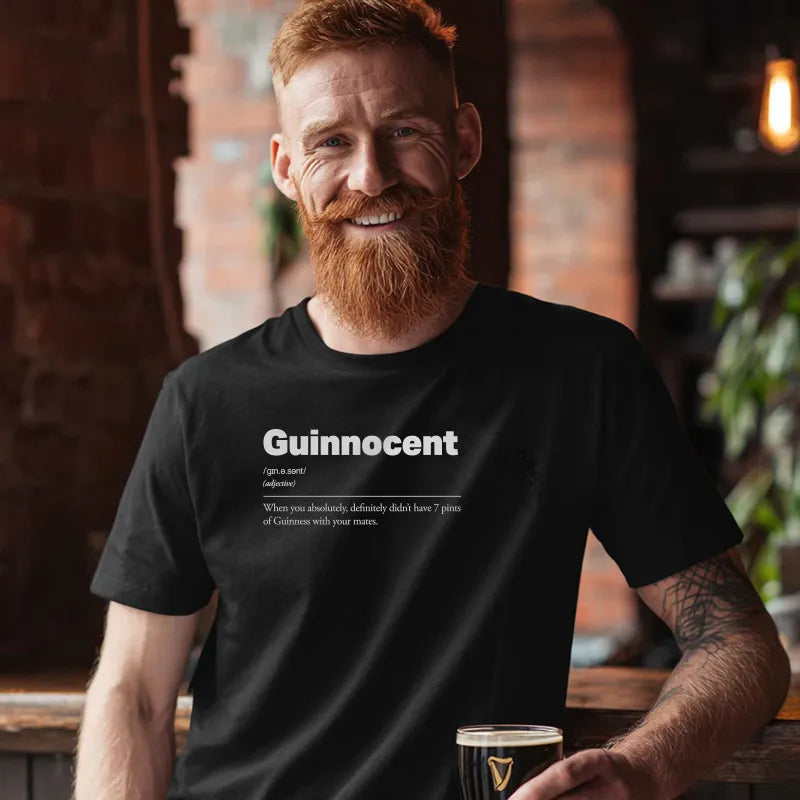 Man wearing a black t-shirt with 'Guinnocent' text, holding a glass in a casual setting. Guinnocent :: When you absolutely, definitely didn't have 7 pints of Guinness with your mates.