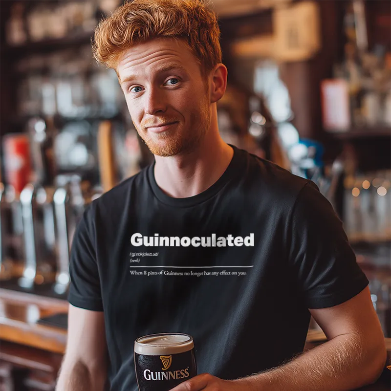 Man holding a Guinness beer mug in a bar setting wearing a black t-shirt reading Guinnoculated :: When 8 pints of Guinness no longer has any effect on you.