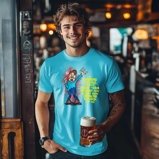 Young man holding a beer in a bar wearing a blue tee shirt with a cartoon character and humorous text saying 'If drinking alcohol affects short term memory just imagine what drinking alcohol can do'