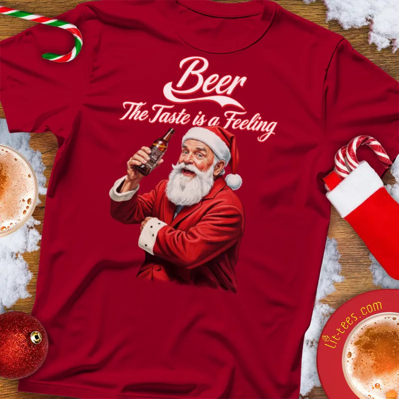 Red Christmas t-shirt with Santa Claus holding a beer bottle and text 'Beer The Taste is a Feeling' on a festive background.