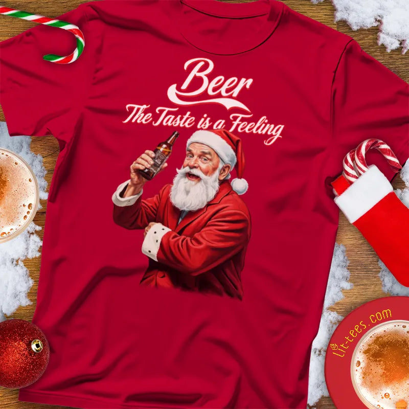 Red Christmas themed t-shirt with Santa Claus holding a beer bottle and text 'Beer The Taste is a Feeling' on a festive background.