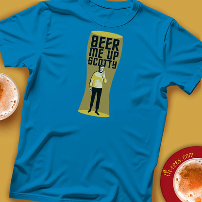 Blue t-shirt with a graphic design of a character holding a beer glass with 'Beer Me Up Scotty' text, placed on a yellow surface with beer glasses