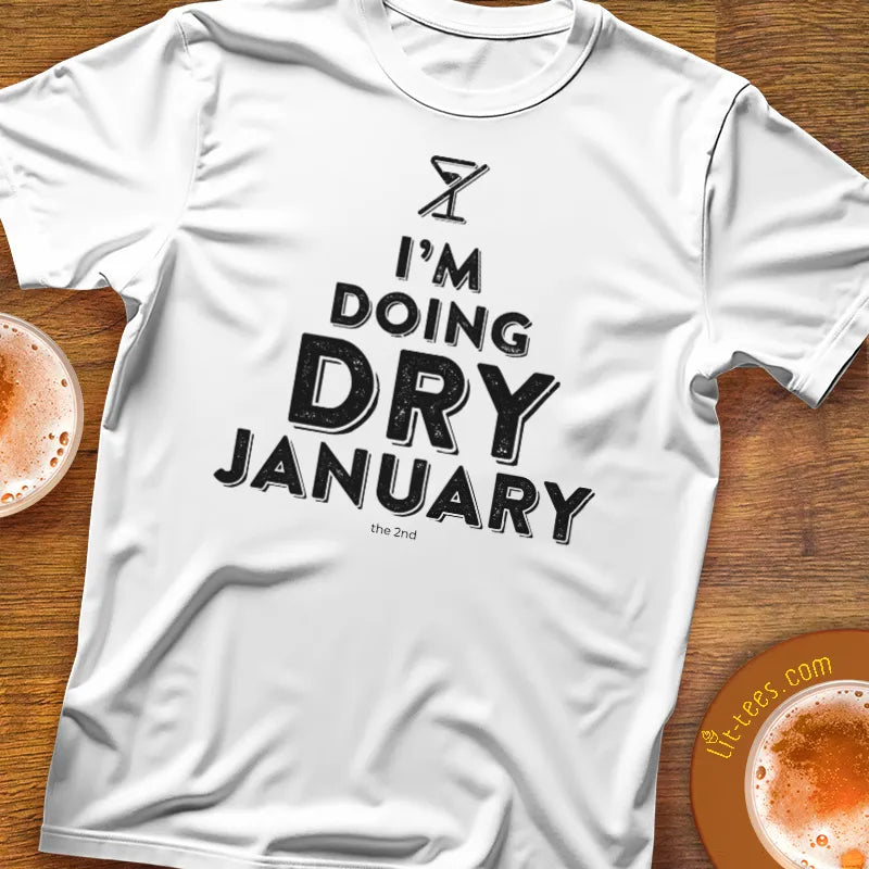 White t-shirt with 'I'm doing Dry January' text on a wooden surface with drinks.