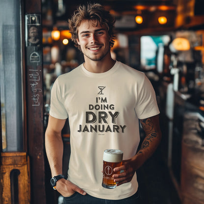 Man holding a beer in a bar wearing a 'I'm Doing Dry January' t-shirt.