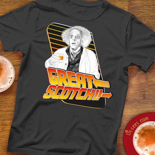 Black t-shirt with a graphic design of a character and 'GREAT SCOTCH!!' text on a wooden surface.