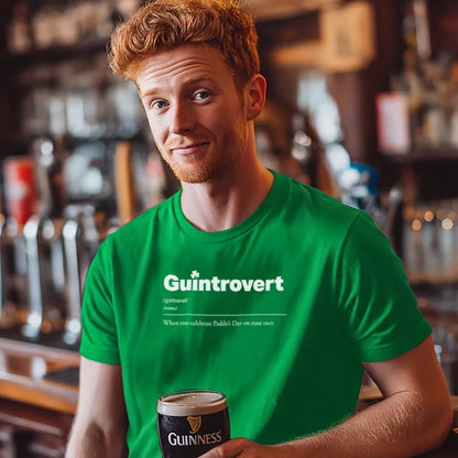 Man in a green 'Guintrovert' t-shirt holding a Guinness in a bar setting.