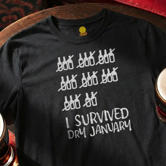 Black t-shirt with white graphic and text 'I Survived Dry January' on a wooden surface.