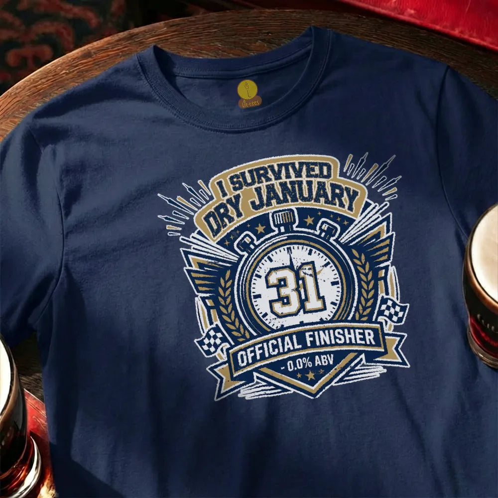 Navy blue t-shirt with 'I Survived Dry January' design on a wooden surface with a glass of beer.