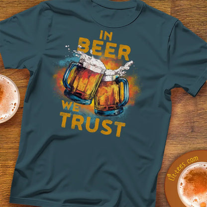 Teal t-shirt with 'In Beer We Trust' graphic on a wooden surface with beer mugs.