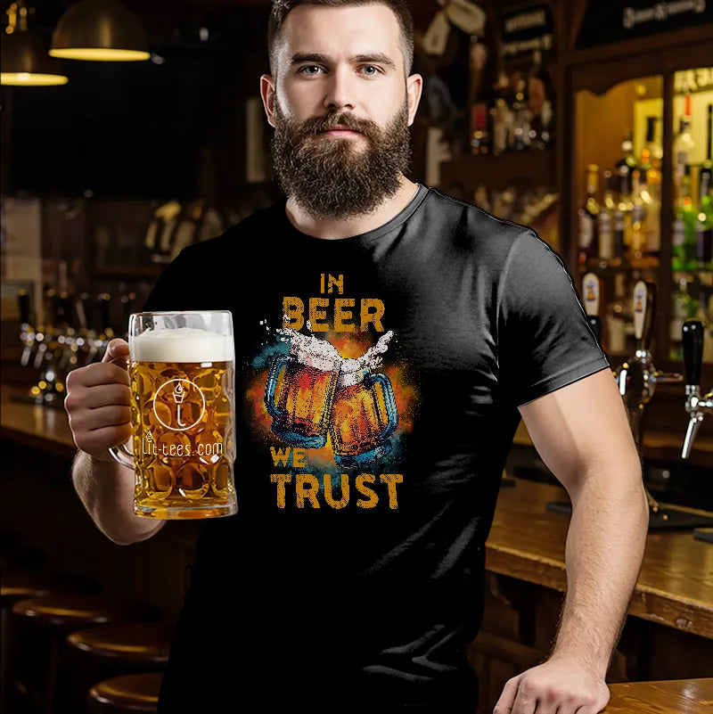 Man holding a beer mug wearing a black t-shirt with 'In Beer We Trust' design in a bar setting.