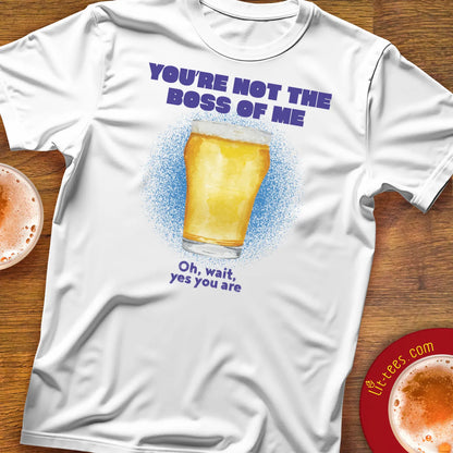 White t-shirt saying 'You're not the boss of me' with a beer graphic and text on a wooden surface with drinks.