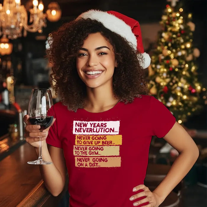 Woman wearing a Christmas themed red shirt with New Year's Neverlution text, holding a glass of wine in a festive setting. Glass has lit-tees.com printed on it.