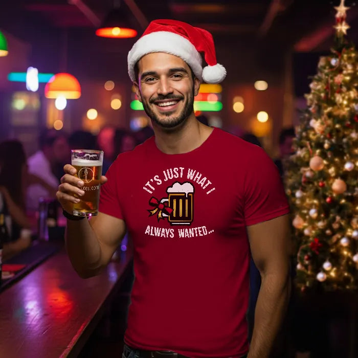 Man wearing a Santa hat and red t-shirt reading 'Just what I always wanted', holding a beer in a bar setting with Christmas decorations.