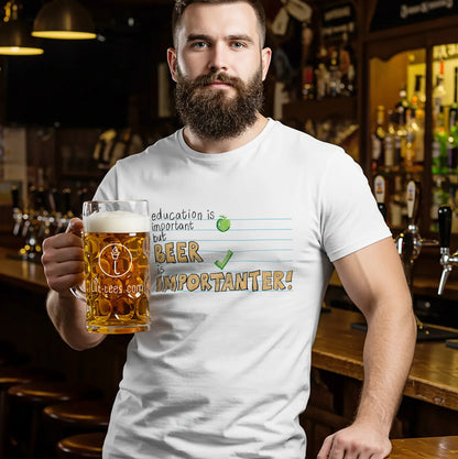 Man wearing a white tee shirt saying 'Education is important but beer is importanter' in typographical style holding a beer in a bar setting.