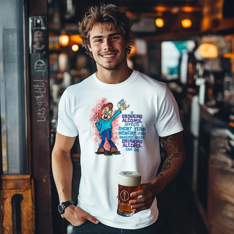 Man holding a beer in a bar wearing a white tee shirt with a cartoon character and humorous text saying 'If drinking alcohol affects short term memory just imagine what drinking alcohol can do' 
