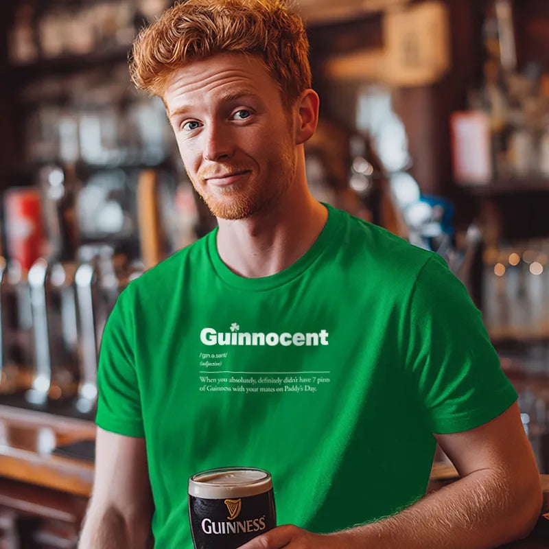 Man wearing a green 'Guinnocent' t-shirt holding a pint of Guinness in a bar setting.