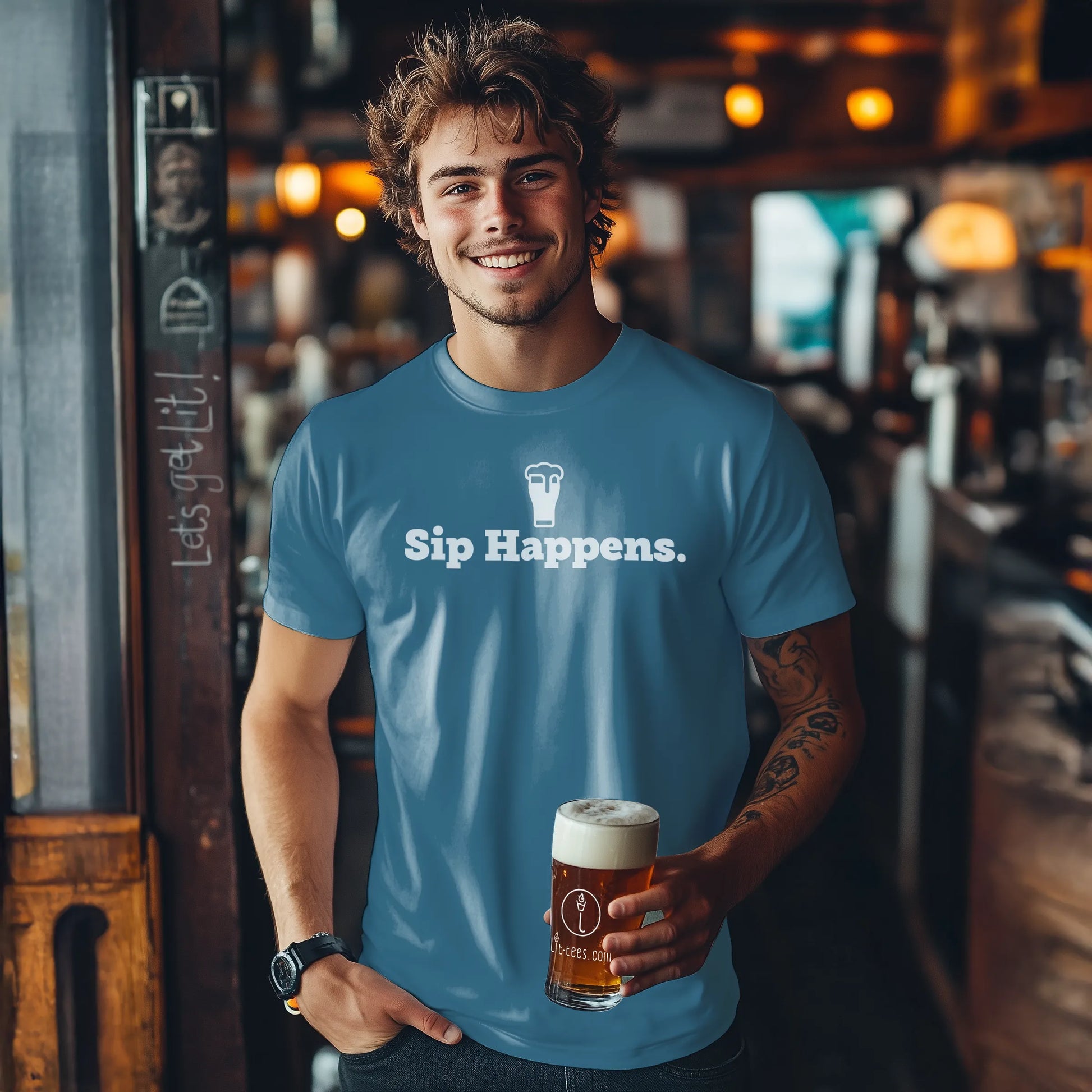 Man wearing an Indigo blue t-shirt with 'Sip Happens.' holding a beer mug in a bar setting.