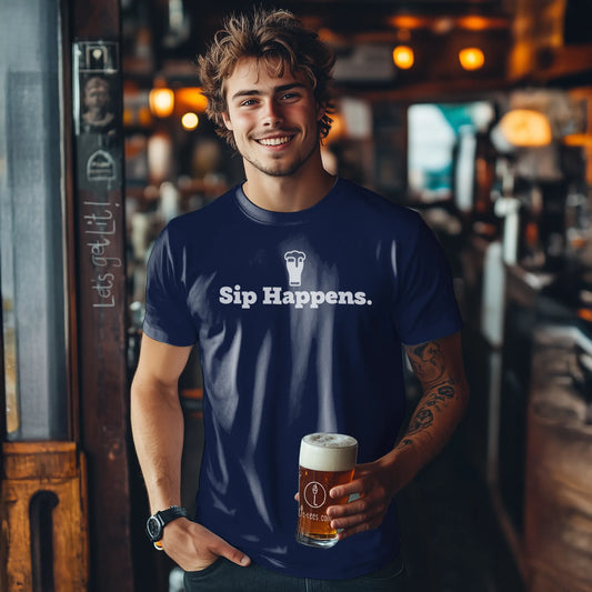 Man wearing a blue t-shirt with 'Sip Happens.' holding a beer in a bar setting